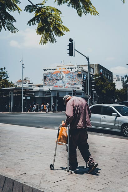 Photo by Dmitry Shamis man in black jacket walking on sidewalk with walker during daytime
